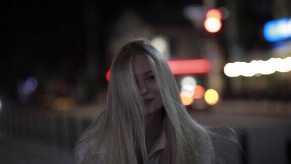 长头发的金发女人在夜晚的城市里吹吻