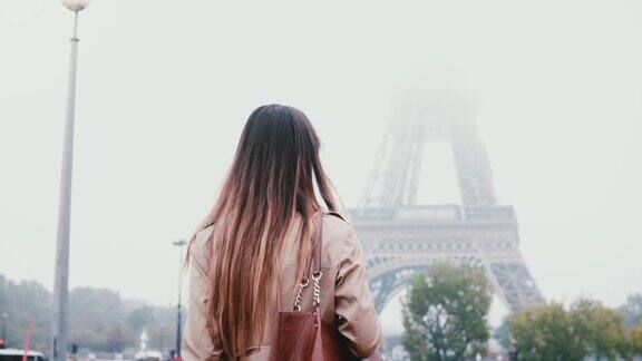 年轻时尚的女人走在巴黎市中心的背影在法国的清晨浓雾和看埃菲尔铁塔