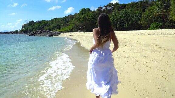 一个穿着白色裙子的女孩正沿着海边跑