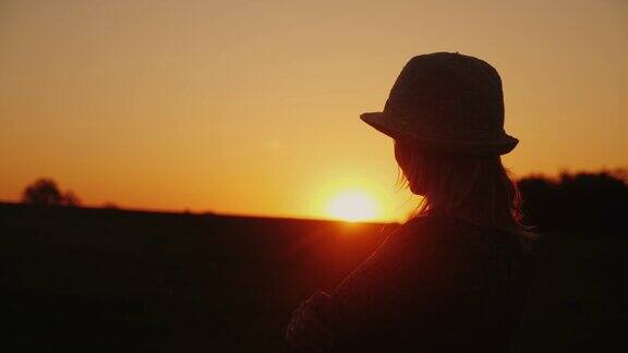 一个戴着帽子的年轻女子在风景如画的地方欣赏日落