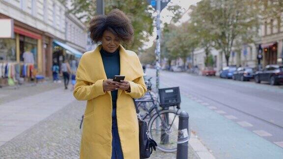穿着夹克的女人在人行道上用智能手机