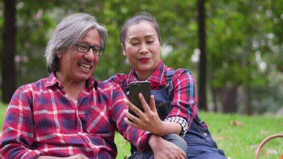 慢镜头:一对情侣通过智能手机在草地上进行视频通话