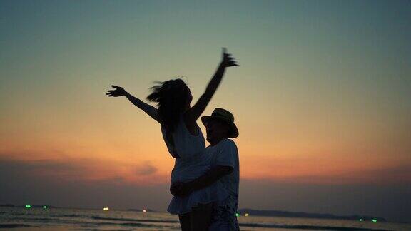 一对亚洲夫妇在日落的沙滩上跳舞