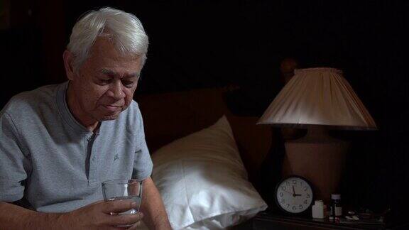 一个抑郁的老年人坐在床上由于失眠和服药而无法入睡