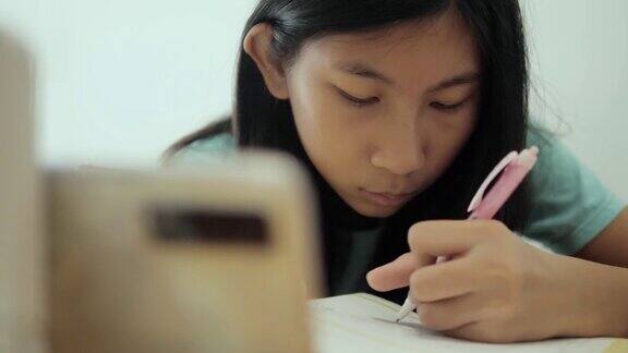 亚洲女孩在COVID-19期间通过智能手机学习在线课程隔离的生活方式概念