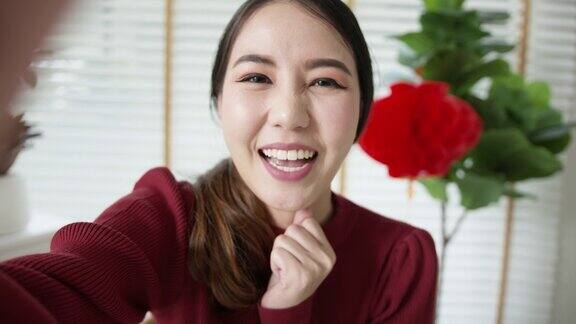 观点自拍视频通话的美丽迷人的年轻亚洲女士在红色春节庆祝服装快乐的微笑交谈和看相机手机祝农历节日