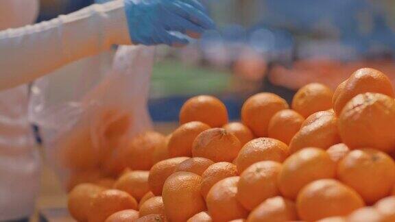 特写镜头一个女人的手拿起橙子放进袋子里在超级市场买橙子超市的柜台上有许多橘子4kProRes