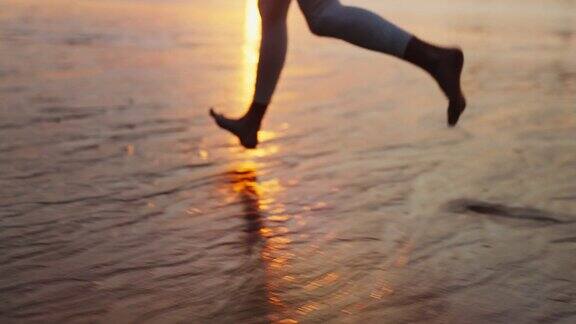 海岸慢跑训练享受日落和自由的女人赤脚在潮湿的沙滩上奔跑