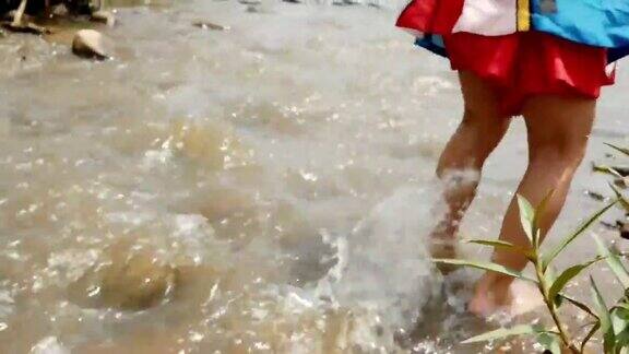 小男孩的双腿在乡村的浅溪中行走童年幸福节约用水