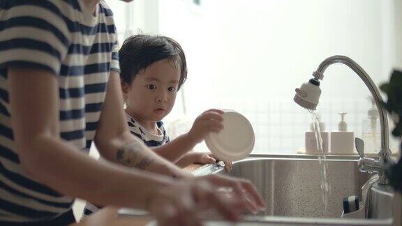 年轻的亚洲妇女和婴儿在厨房洗碗