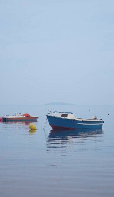 雾蒙蒙的清晨海边小船的宁静景象
