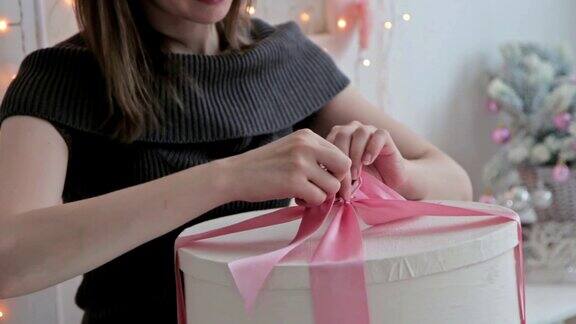 快乐的年轻女子在圣诞礼物盒上打一个蝴蝶结