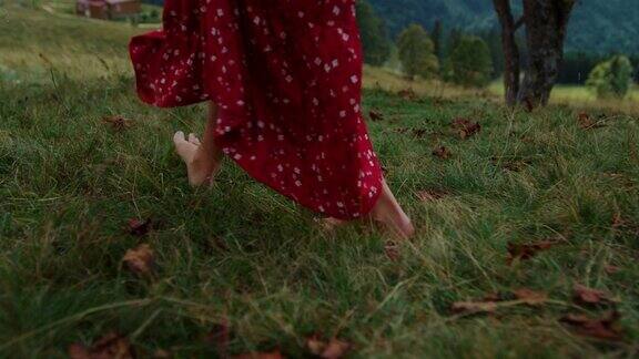 光着脚的女人走在绿色的草地上不知名的女孩踩在草地上