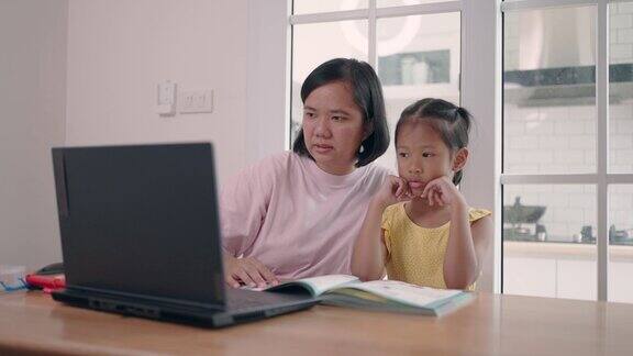 母亲在家用笔记本电脑照顾女儿上网学习