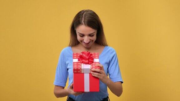 肖像惊讶的女人打开红色节日礼品盒与弓渴望的礼物摆孤立