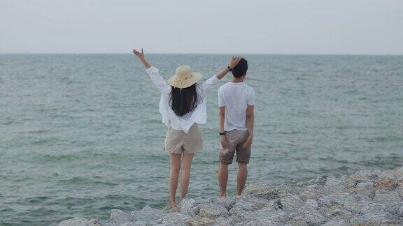在假日的周末一对相爱的亚洲夫妇举起手臂庆祝成功浪漫的情侣在海滩度假旅行