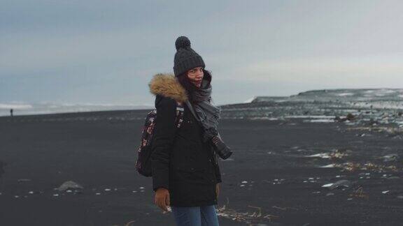 年轻女子旅行者走在冰岛的火山黑沙滩上慢动作镜头维克附近的Reynisfjara海滩