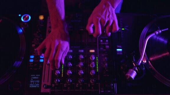 俱乐部DJ混合音乐轨道与混音器在近距离视频音乐节目主持人在夜总会的派对上播放电子音乐