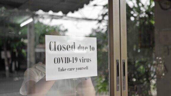 这名女孩正在关闭商店的标志因Covid-19病毒大流行爆发商店关闭