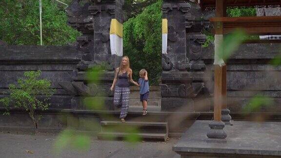 这是一名年轻女子和她的小儿子参观巴厘岛乌布村果阿加贾的大象洞的慢动作镜头