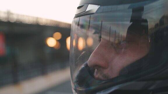 年轻迷人的摩托车手在街道上戴着黑色的头盔男人摩托车骑士日落