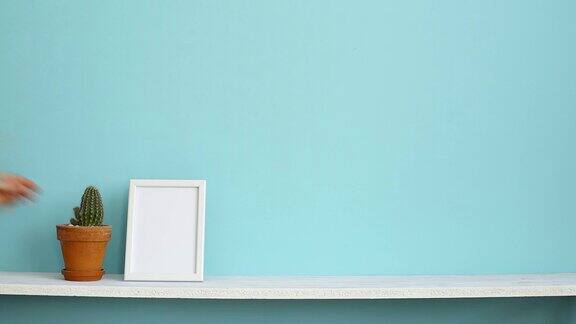 现代房间装饰与画框模型白色的架子对着淡蓝色的墙壁上面放着盆栽的仙人掌