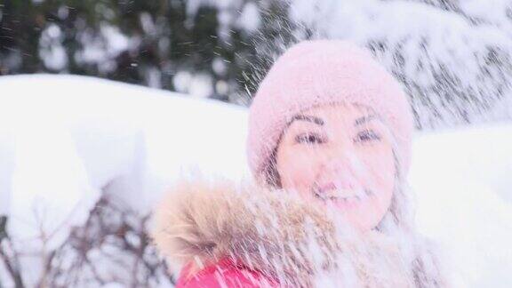 在一个阳光明媚的冬日穿着红色夹克的年轻女子在空中抛雪