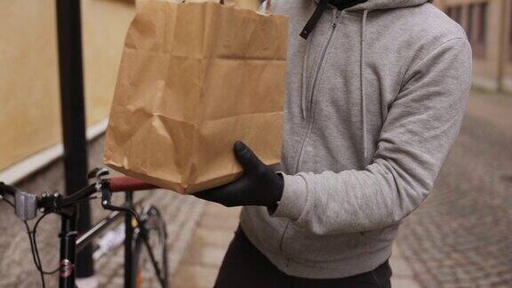 一名女子从自行车外卖员手中接过纸袋