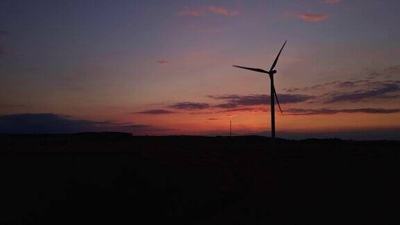 夕阳下田野里风车涡轮机的剪影旋转的风力发电机