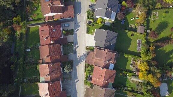 空中俯瞰在有排屋和绿色花园草坪的郊区城镇上空飞行