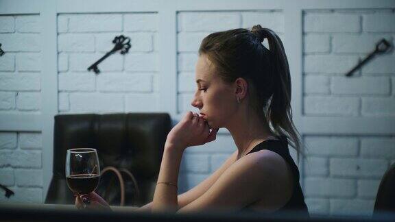 年轻美丽的焦虑的女人正看着一杯红酒转身回头看