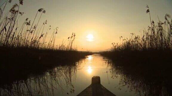日落时在沼泽水域航行的小船