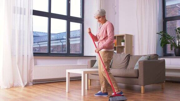 老妇人拿着扫帚扫扫地板