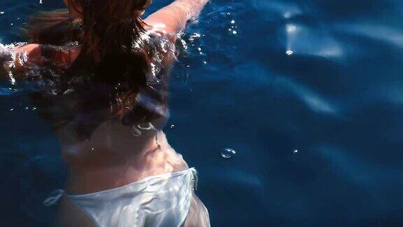 女孩戴着面具在清澈的蓝色海水里浮潜