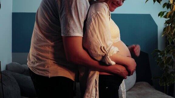 一个怀孕的女人站在一个房间里男人走到她身边拥抱她