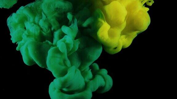 流动的丙烯酸油墨在黑色背景上孤立的水慢动作的多色液体流动缓慢的运动和混合的黄色和绿色油墨流入水中丙烯酸涂料在水中颜色在运动深的空间