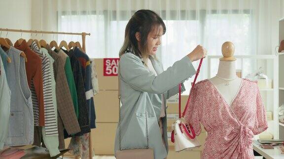 年轻的亚洲女子在商店里用手机直播向顾客展示新款手袋中小企业小企业电子商务