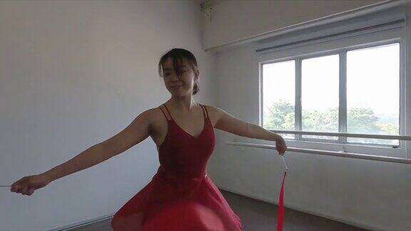 亚洲华裔年轻女芭蕾舞演员在演播室里旋转彩带