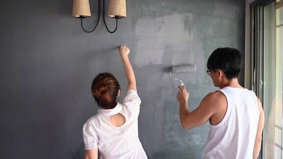 一对亚洲华人夫妇正在粉刷他们的房子