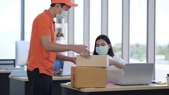亚洲女商人戴着面具从快递员那里收到一个包裹