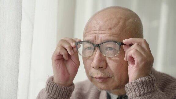 窗前的一位中国老人戴着老花镜凝视着前方
