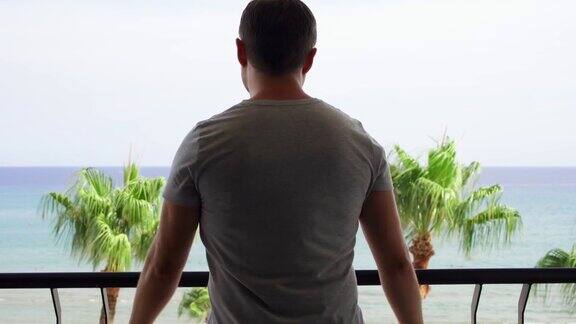 男子打开滑动阳台玻璃门从阳台上欣赏地中海海景