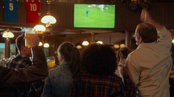 一群多元文化的朋友在体育酒吧看电视直播的足球比赛快乐的球迷欢呼呐喊当球队进球并赢得足球世界杯时年轻人庆祝