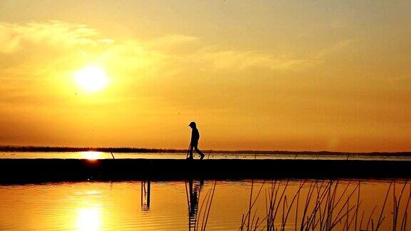 日落时分男孩在河边的码头上水中的倒影少年们