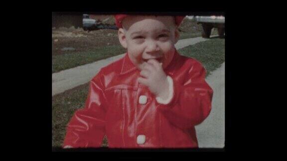 1961年可爱的小男孩穿着红色外套和帽子与母亲和古董车