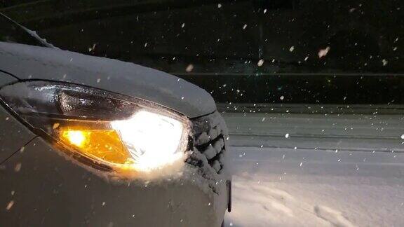 汽车的前灯照亮了雪景缓慢的运动