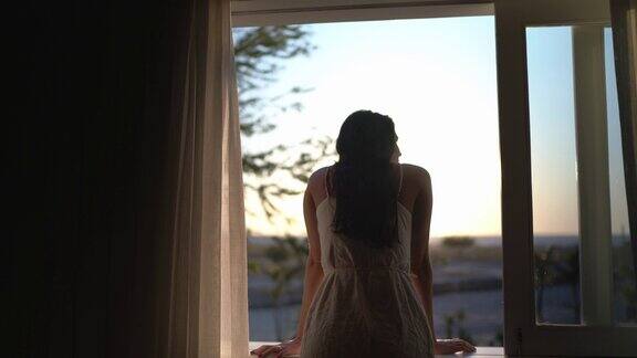 年轻女子透过酒店窗户往外看