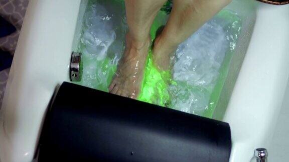 女人洗她的脚在小浴盆前做足疗