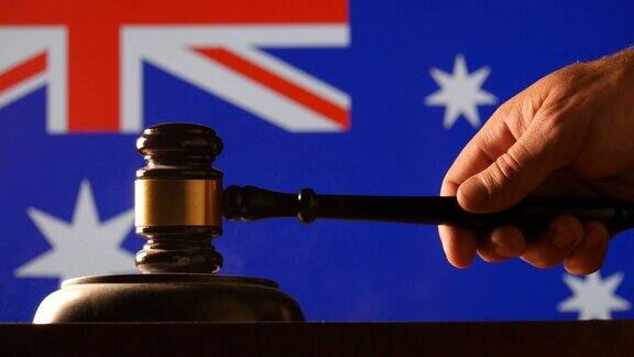 法官在以旗帜为背景的澳大利亚法院用锤子敲击小木槌下达命令