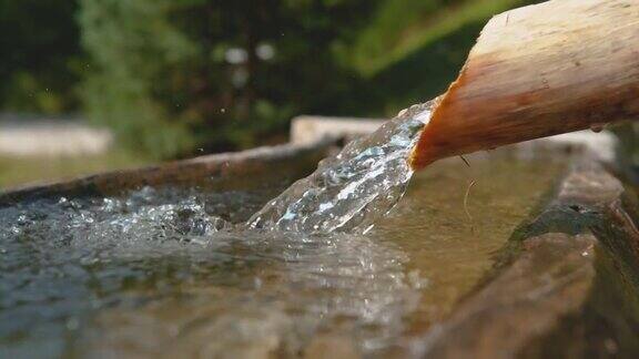 慢动作:清澈的水流通过木管流入盆内